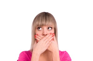 Close-up of a young woman with her finger on lips. Beautiful girl with a finger on her lips, showing silence. Young female gesturing silence. Shhh... this girl's got a secret